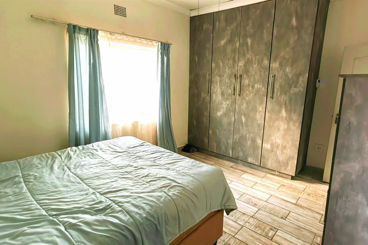 A bedroom featuring tiled flooring and floor-to-ceiling built-in cupboards with a textured finish.