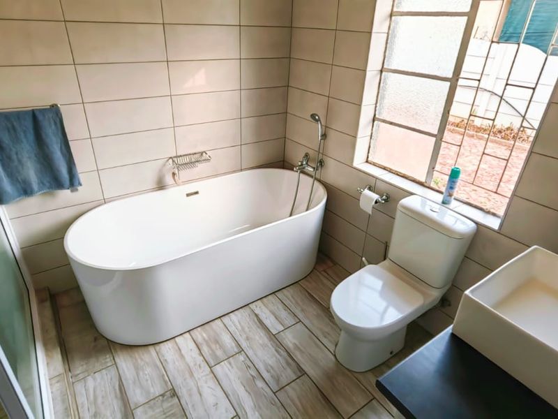 Modern bathroom featuring a freestanding bathtub, separate shower enclosure, vessel sink vanity, and neutral wall tiling.