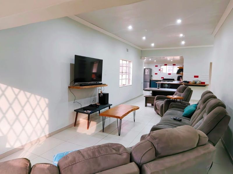 An open-plan living area featuring tiled flooring, recessed downlights, and a seamless transition into a functional kitchen space.