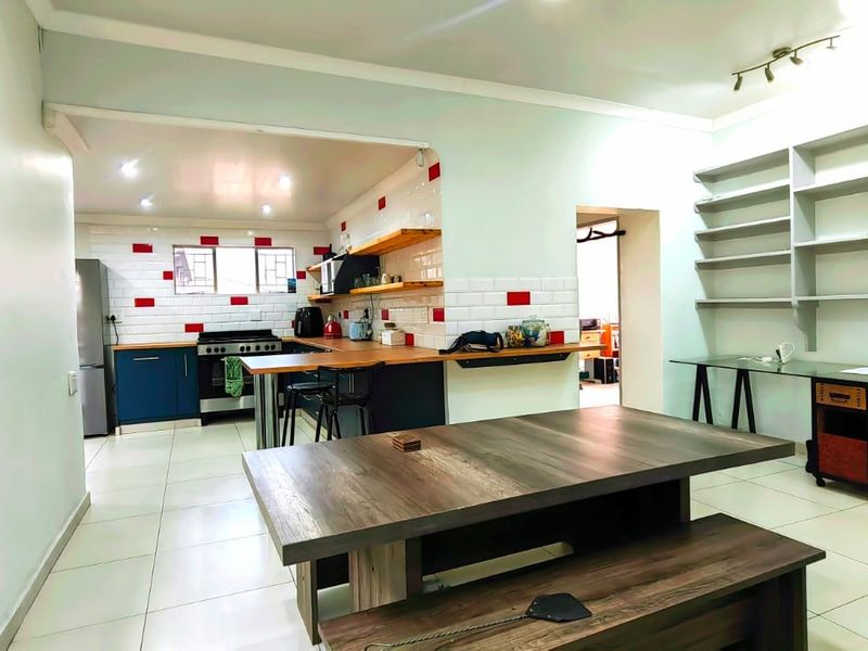 Open-plan living and kitchen area featuring modern subway tile backsplash, wooden countertops, built-in shelving, and tiled flooring throughout.