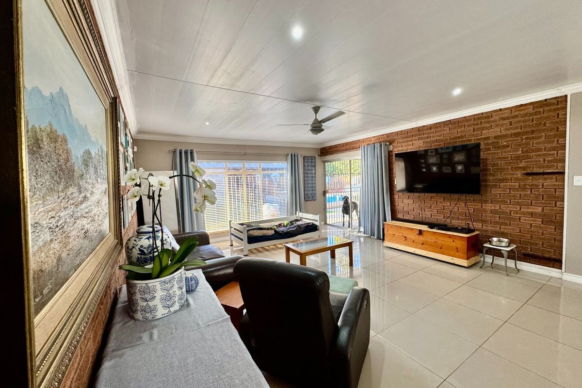 Spacious living room featuring an exposed brick feature wall, large format floor tiles, and direct access to the outdoor area through sliding glass doors.
