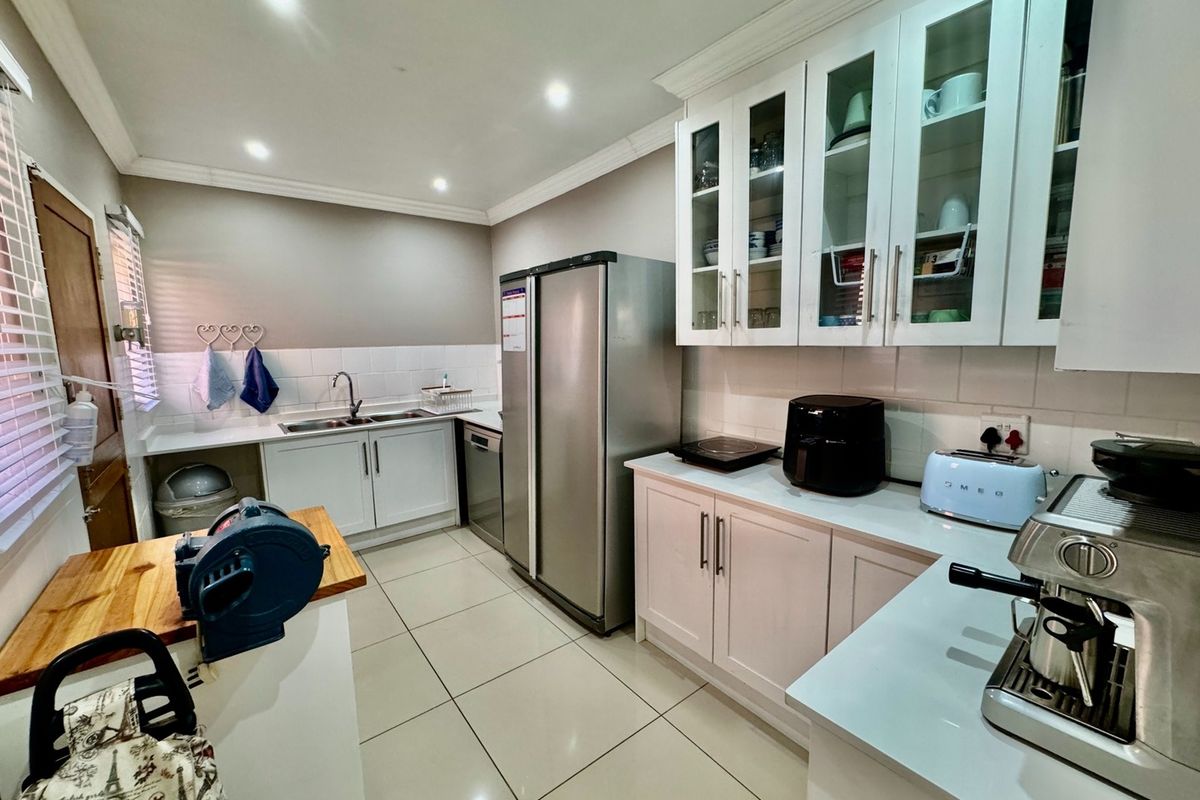 A functional kitchen featuring white cabinetry, tiled backsplash, double sink, and tiled flooring with recessed lighting.