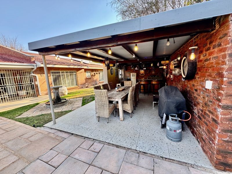 A covered outdoor patio area featuring exposed brick walls, paved flooring, and integrated lighting, ideal for alfresco dining and entertaining.