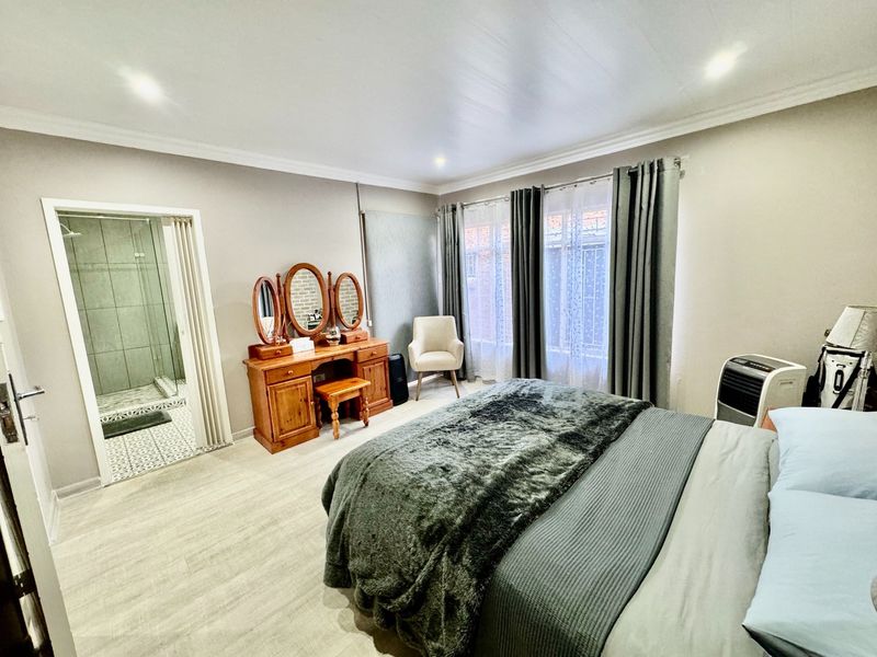 A well-maintained bedroom featuring laminate flooring, recessed lighting, and direct access to an en-suite bathroom.