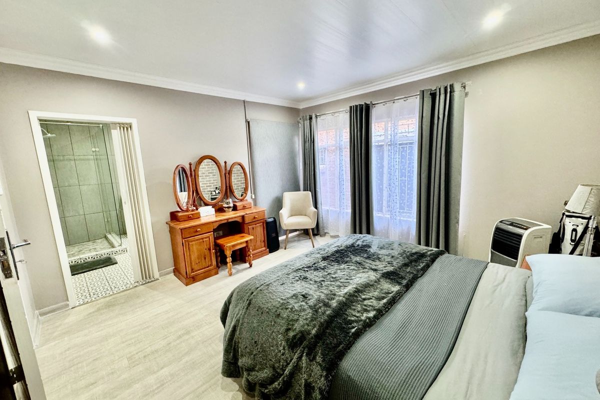A well-maintained bedroom featuring laminate flooring, recessed lighting, and direct access to an en-suite bathroom.