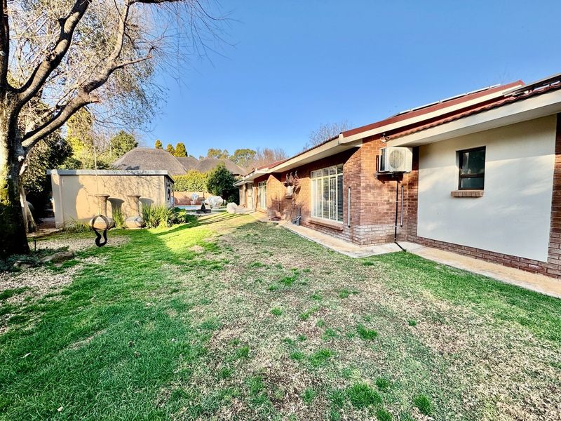 A view of the rear exterior of the house featuring a brick facade, lawn area, and an installed air conditioning unit.