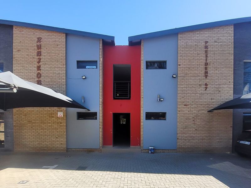 Front elevation of a modern apartment complex featuring a brick and painted facade with dedicated shade sail parking bays.