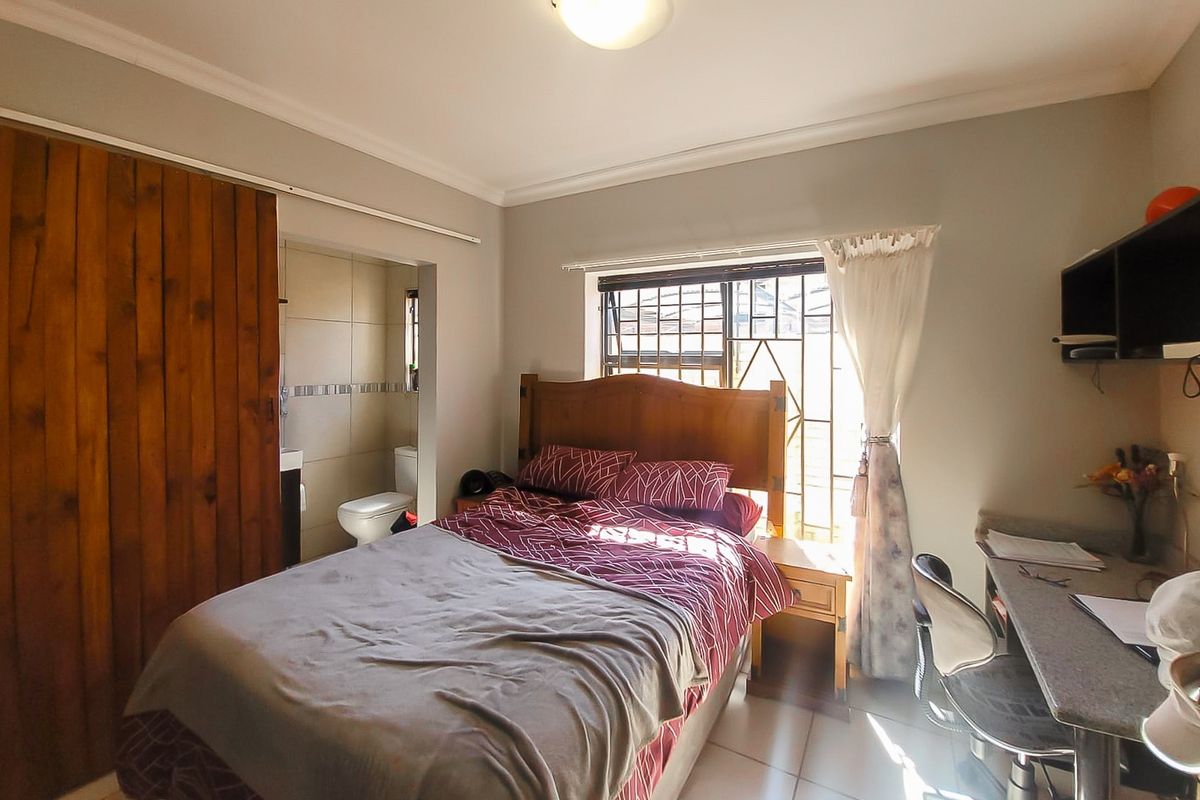 A functional bedroom featuring tiled flooring, a built-in wardrobe with a sliding door, and direct access to an en-suite bathroom.