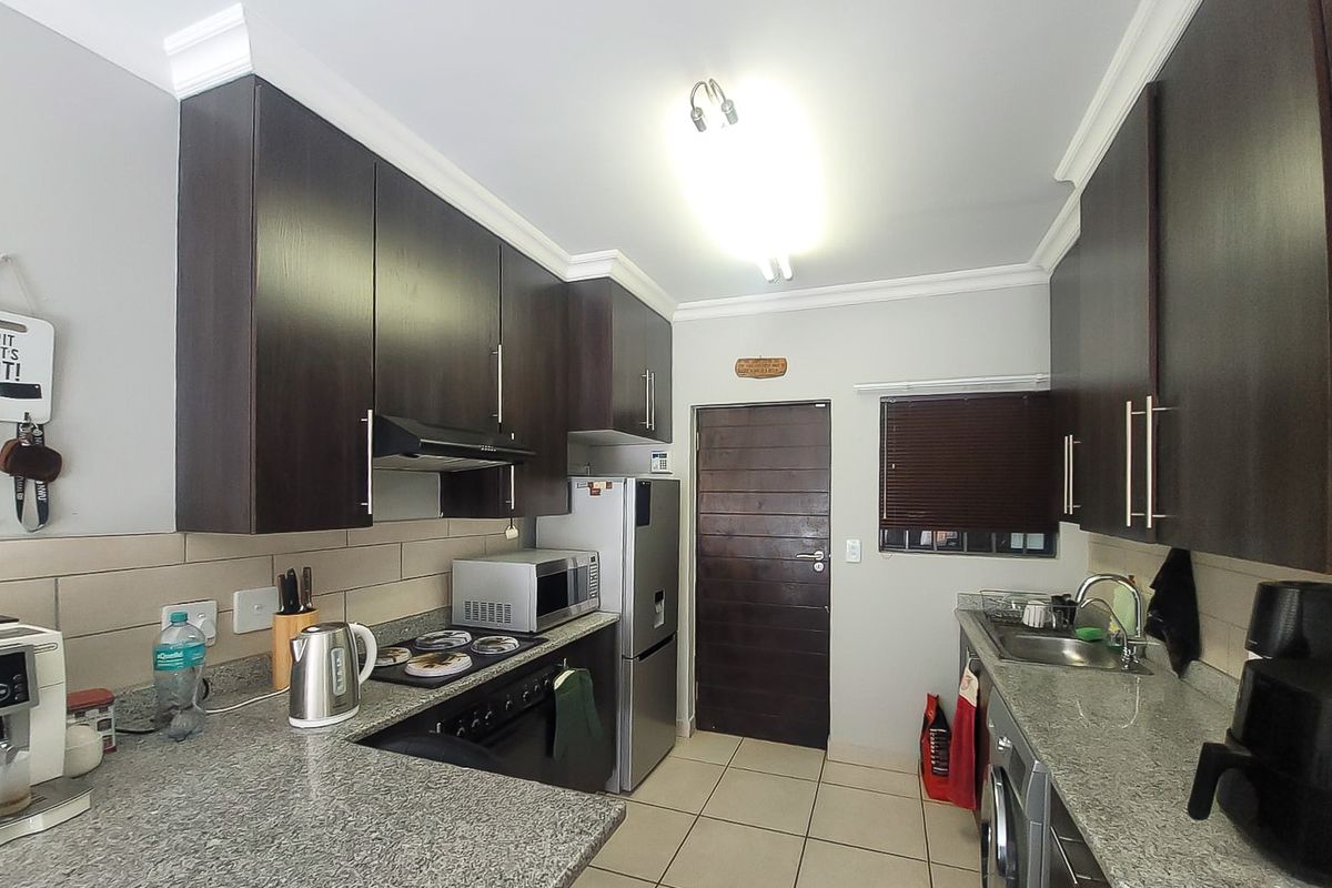 A functional kitchen featuring dark wood cabinetry, granite countertops, tiled backsplash, and integrated appliances, providing a practical and well-maintained cooking space.