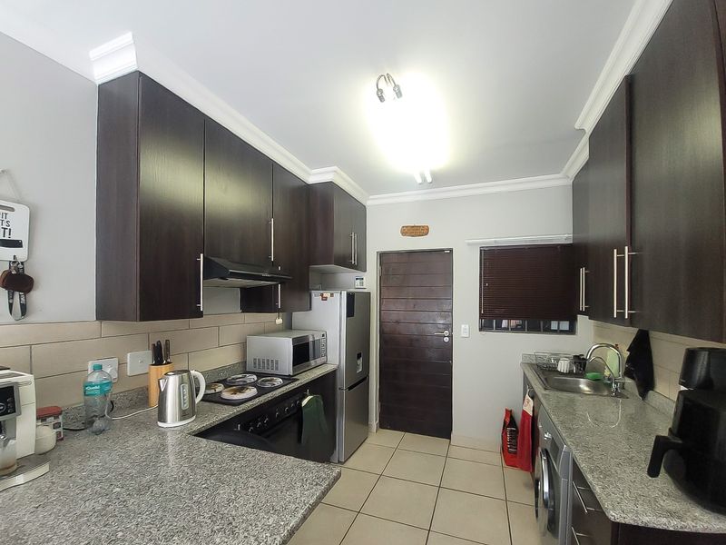 A functional kitchen featuring dark wood cabinetry, granite countertops, tiled backsplash, and integrated appliances, providing a practical and well-maintained cooking space.