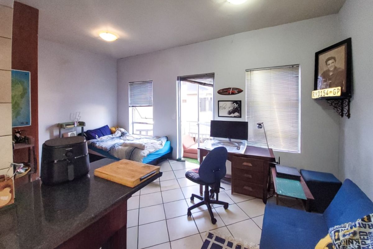 Open-plan living area featuring tiled flooring, granite kitchen counter, and access to a balcony through a sliding door.