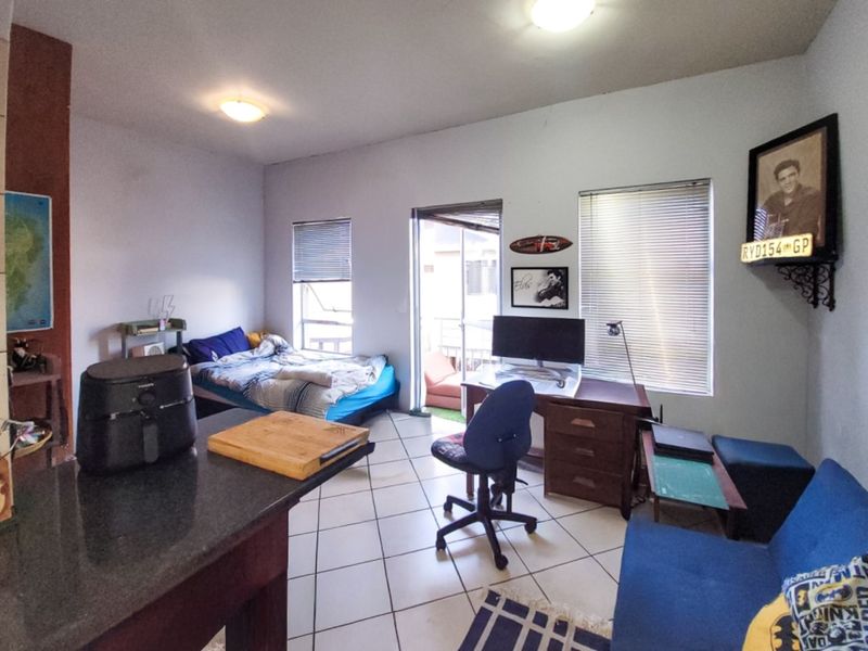 Open-plan living area featuring tiled flooring, granite kitchen counter, and access to a balcony through a sliding door.