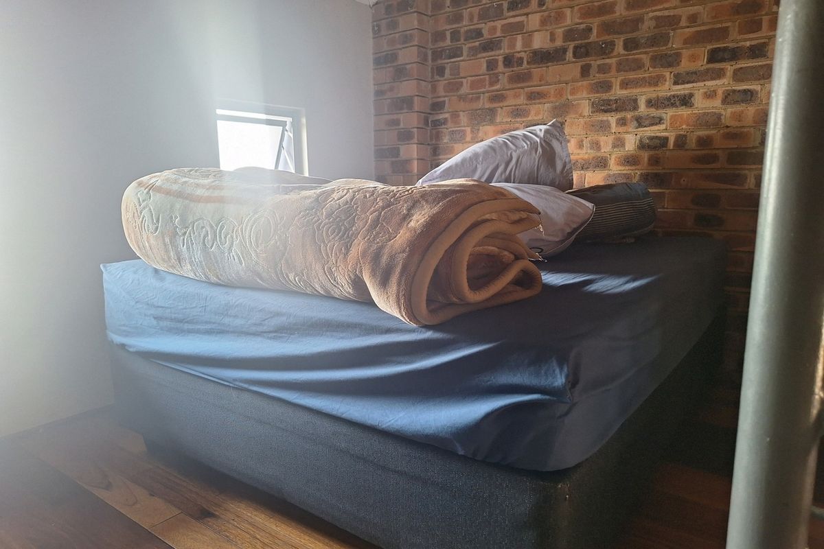 A bedroom featuring a rustic exposed brick feature wall and warm timber flooring, providing a cozy atmosphere.