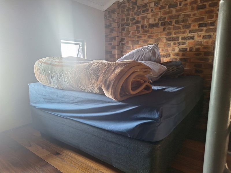 A bedroom featuring a rustic exposed brick feature wall and warm timber flooring, providing a cozy atmosphere.