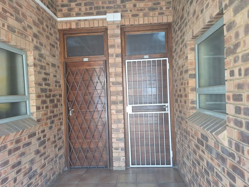 Entrance area featuring exposed brickwork, tiled flooring, and secure timber doors with fitted security gates for two separate apartment units.