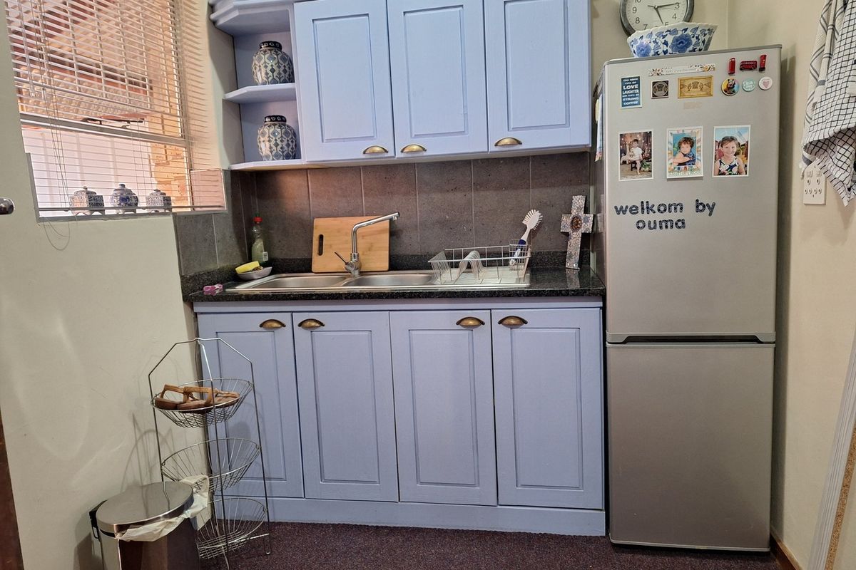 A compact kitchen area featuring light blue cabinetry, a double basin sink with a stone countertop, and a tiled backsplash.