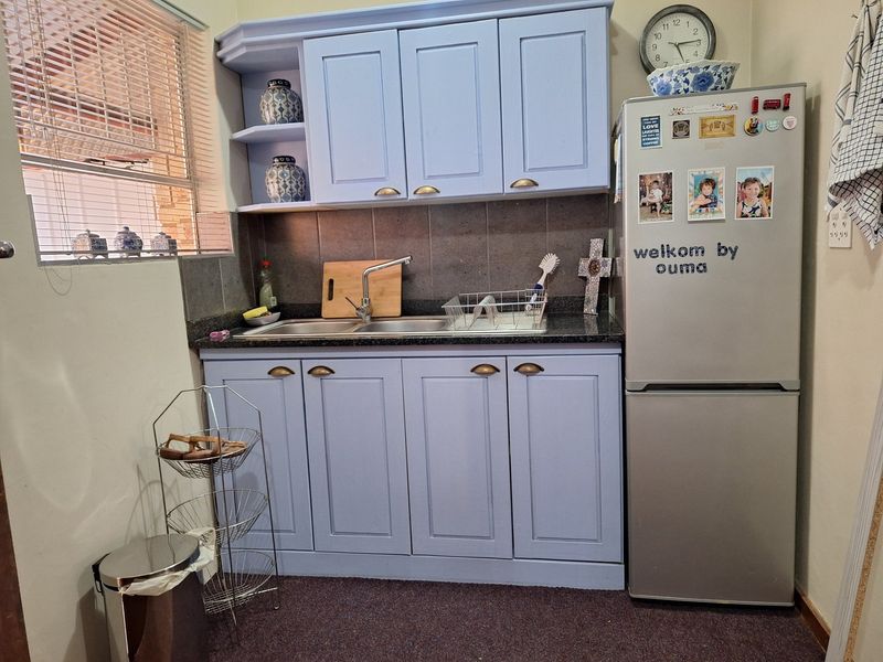 A compact kitchen area featuring light blue cabinetry, a double basin sink with a stone countertop, and a tiled backsplash.