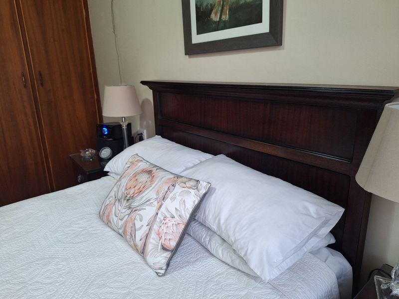 A bedroom featuring a built-in wooden wardrobe and a dark wood headboard.