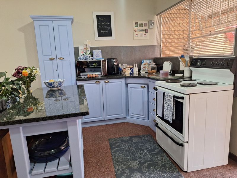A functional kitchen featuring light blue cabinetry, granite countertops, a tiled backsplash, and a freestanding stove with an integrated oven.