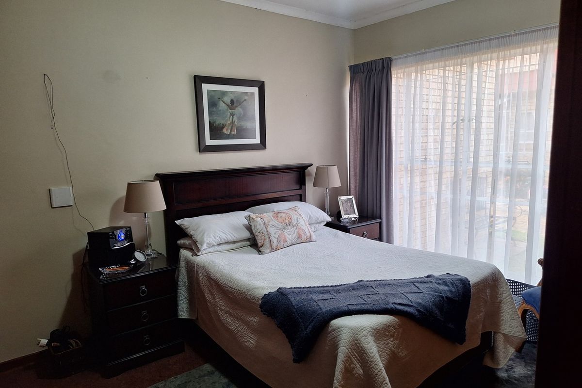 A standard bedroom featuring neutral walls, coving, and large windows with curtain rails, providing natural light.