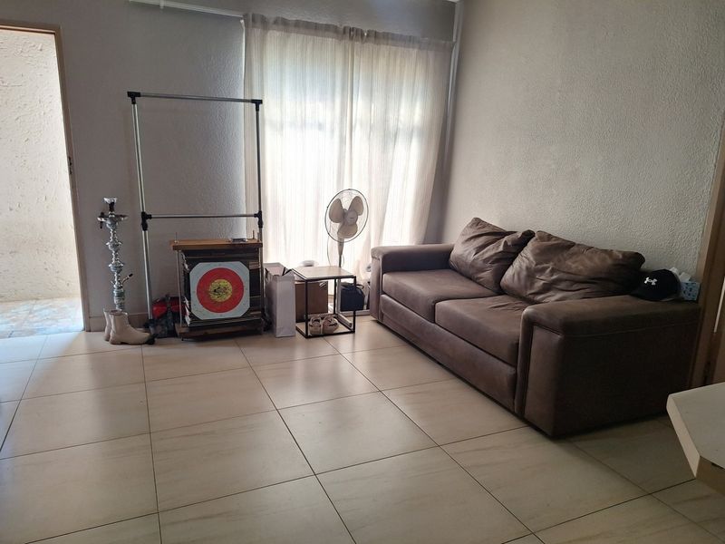 A living room area featuring neutral tiled flooring and access to an outdoor space through a sliding door.
