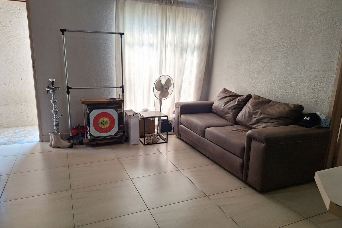 A living room area featuring neutral tiled flooring and access to an outdoor space through a sliding door.