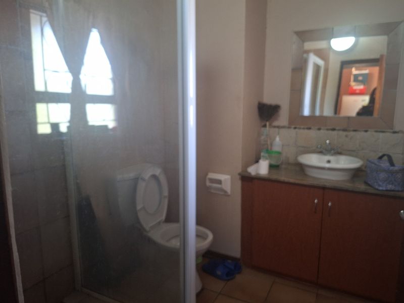 A functional bathroom featuring a shower enclosure, a vanity cabinet with a washbasin, and a wall-mounted mirror.