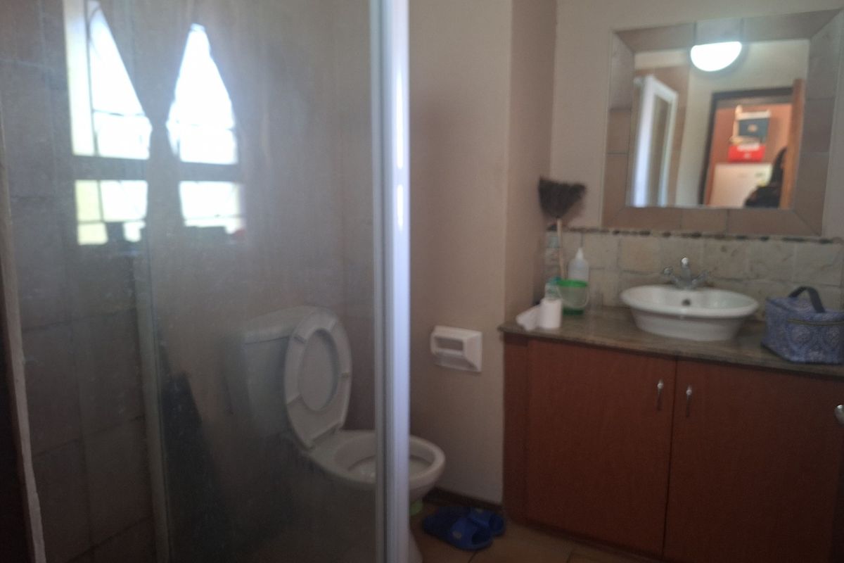 A functional bathroom featuring a shower enclosure, a vanity cabinet with a washbasin, and a wall-mounted mirror.