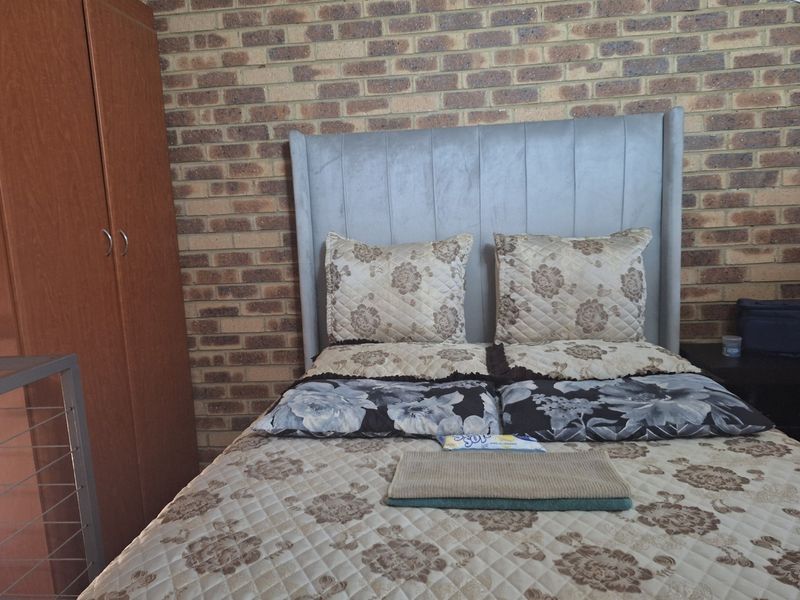 A bedroom featuring an exposed brick feature wall and a built-in wardrobe, offering a rustic aesthetic.