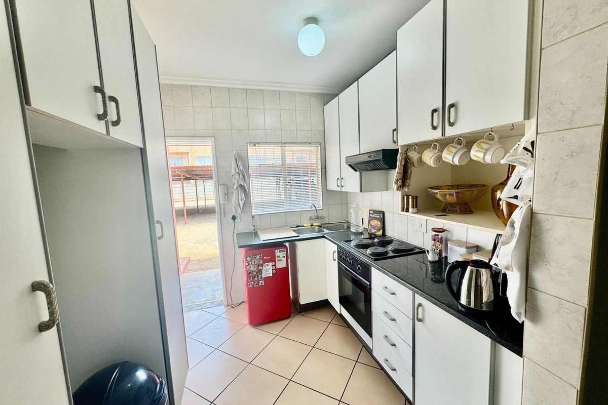 A functional kitchen featuring white cabinetry, granite countertops, built-in oven and hob, tiled backsplash, and direct access to the exterior.
