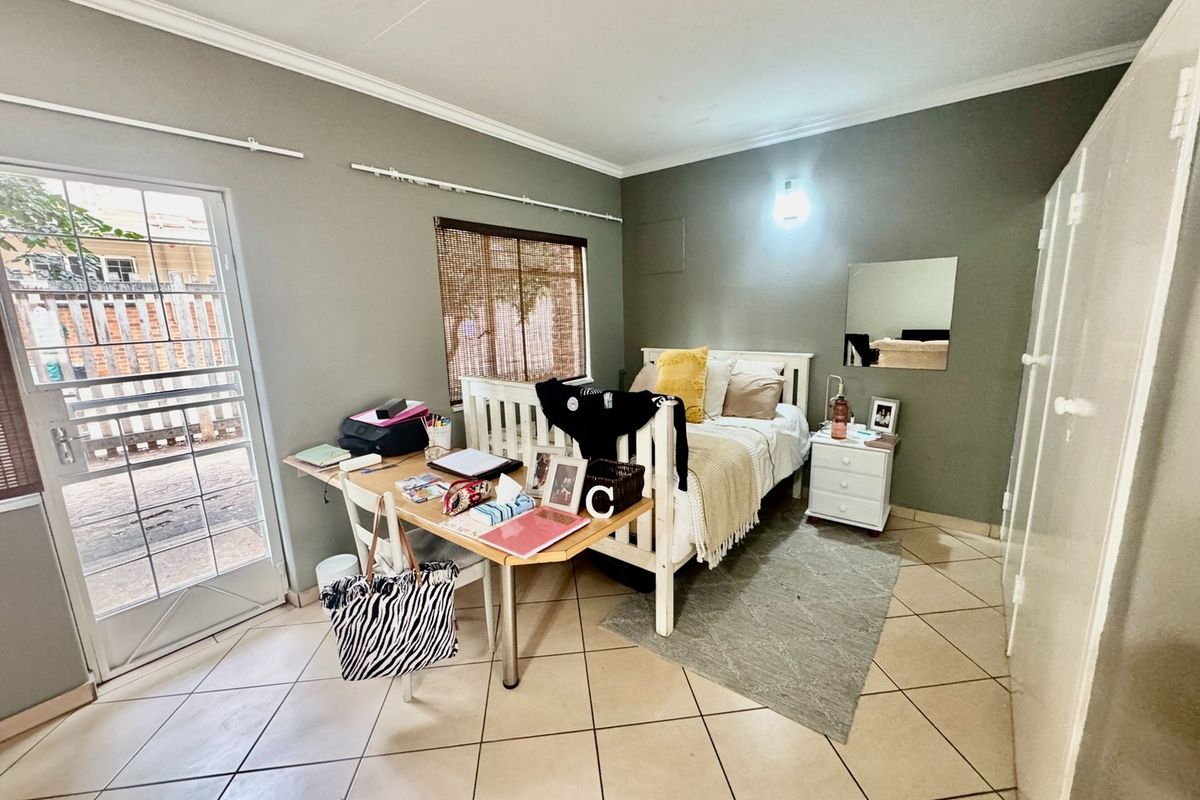 A bedroom featuring tiled flooring, built-in wardrobe storage, and direct access to an outdoor area through a secure sliding door.