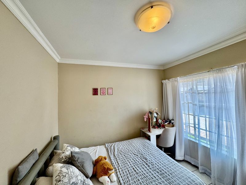 A standard bedroom featuring neutral wall paint, ceiling cornice detailing, and a flush mount light fixture, providing a functional and well-lit living space.