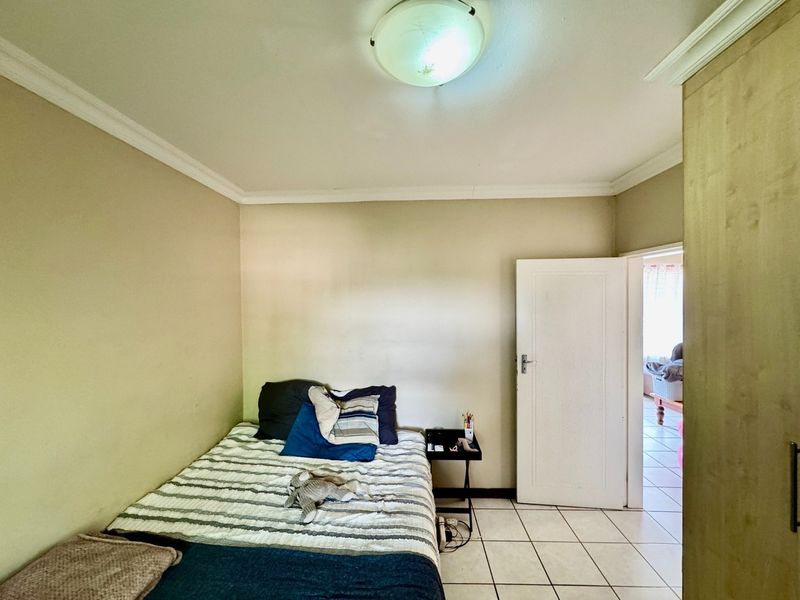 A functional bedroom featuring tiled flooring, a built-in cupboard, and a central ceiling light fixture, offering a neutral base for interior updates.