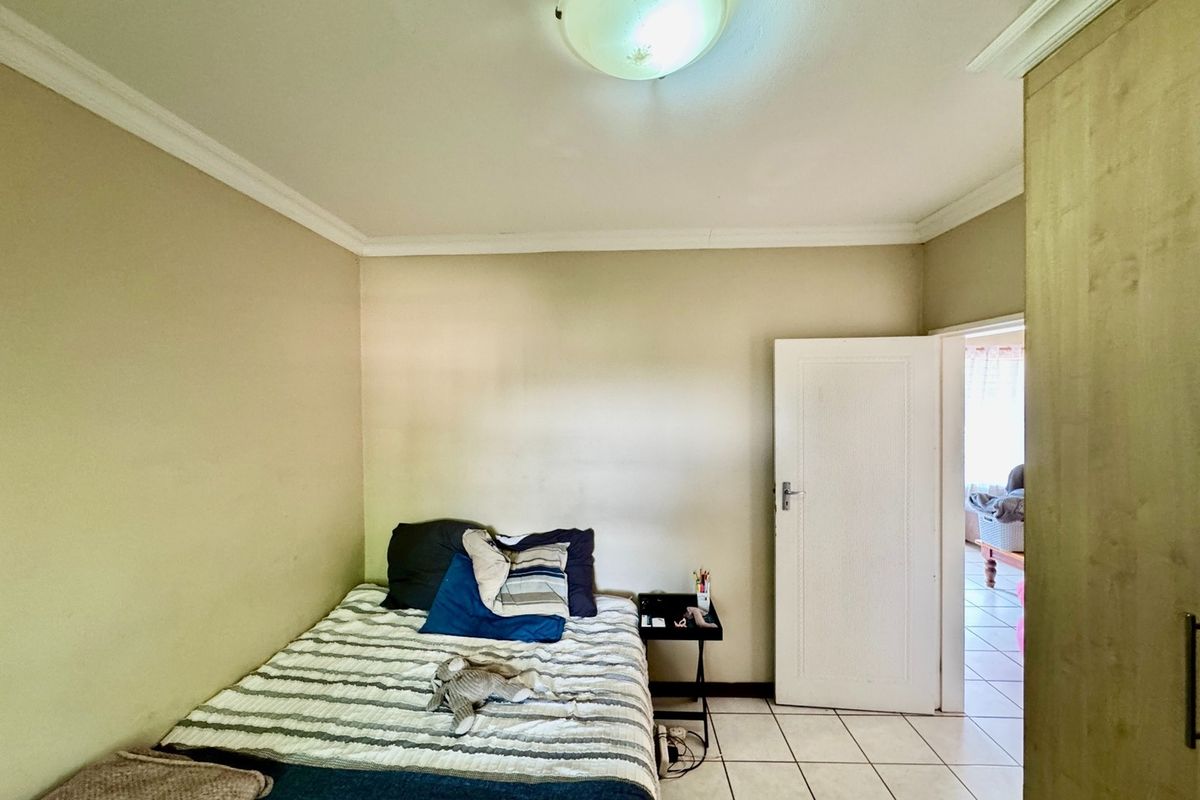 A functional bedroom featuring tiled flooring, a built-in cupboard, and a central ceiling light fixture, offering a neutral base for interior updates.