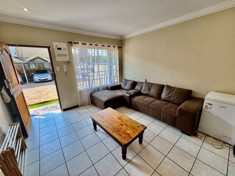 A functional living room featuring tiled flooring, recessed lighting, and decorative cornice, with direct access to the exterior parking area.