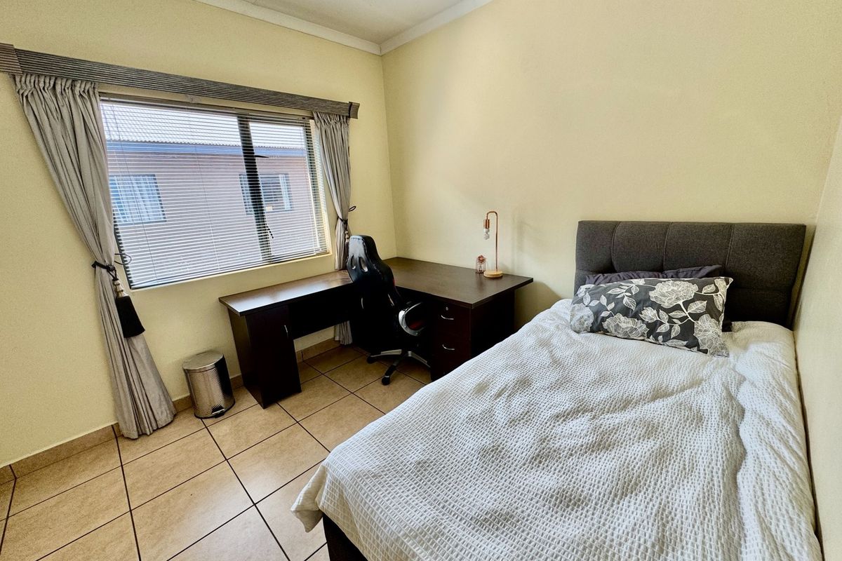 A functional bedroom featuring tiled flooring, a window with fitted blinds, and neutral wall finishes, providing a comfortable and practical living space.