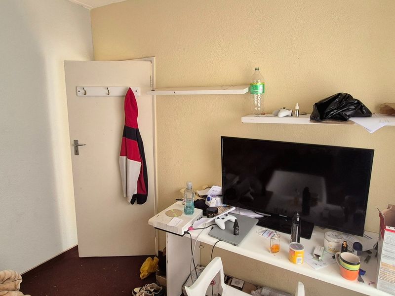 A bedroom featuring built-in wall shelving and a standard interior door with a mounted hook rail.