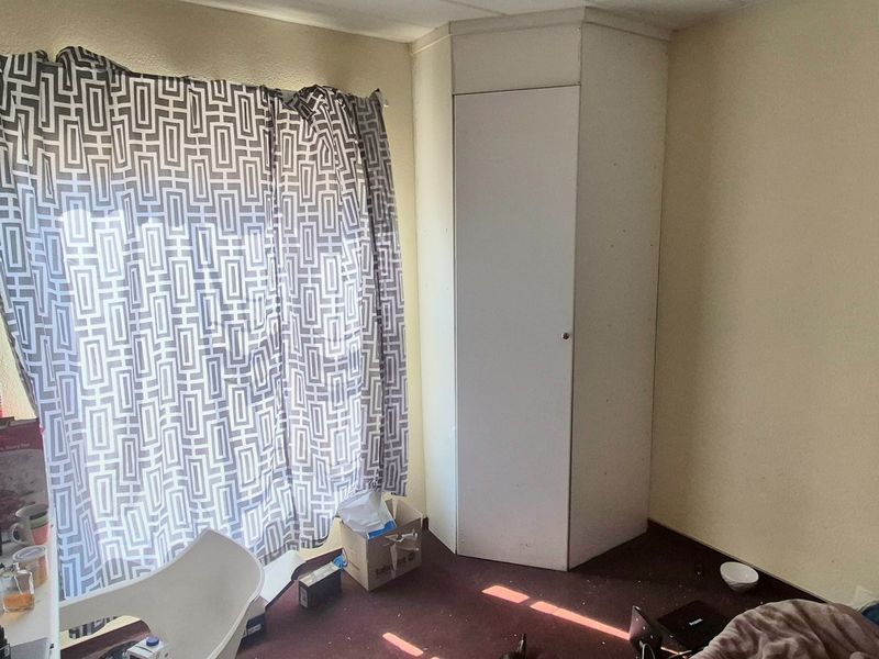 A bedroom featuring a built-in corner cupboard and carpeted flooring, offering a functional space ready for cosmetic updates and modernization.