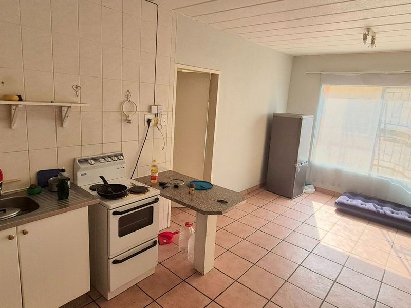 Open-plan kitchen and living area featuring tiled flooring, a breakfast counter, and a functional kitchen layout with a freestanding stove.