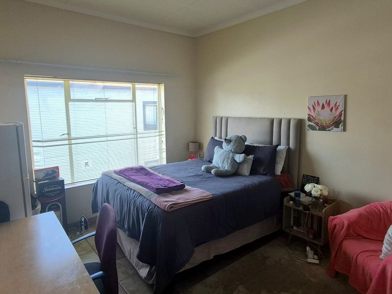 A functional bedroom featuring tiled flooring and a large window that provides natural light to the space.