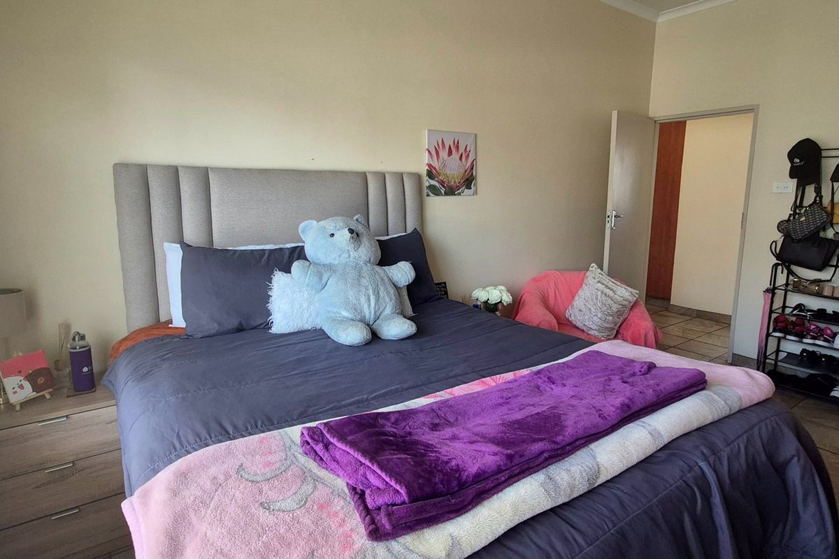 A bedroom featuring tiled flooring, built-in wardrobe storage, and venetian blinds, providing a functional and comfortable living space.
