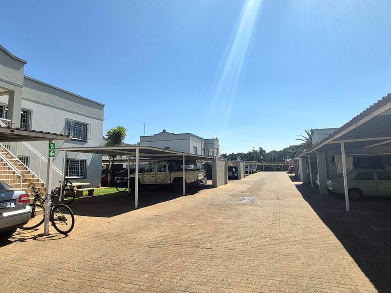 Exterior view of the apartment complex featuring paved driveway access and covered carport parking bays for residents.