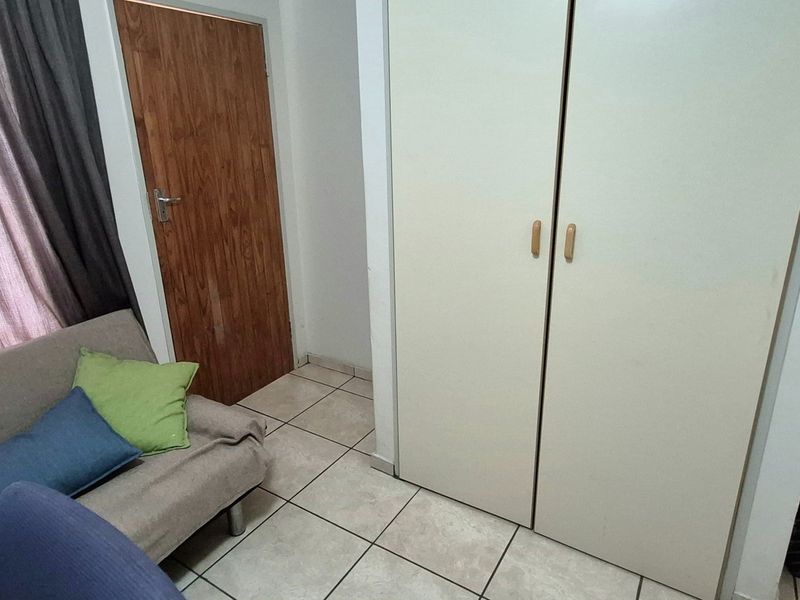 A bedroom featuring tiled flooring and built-in cupboards, providing functional storage space within the apartment.
