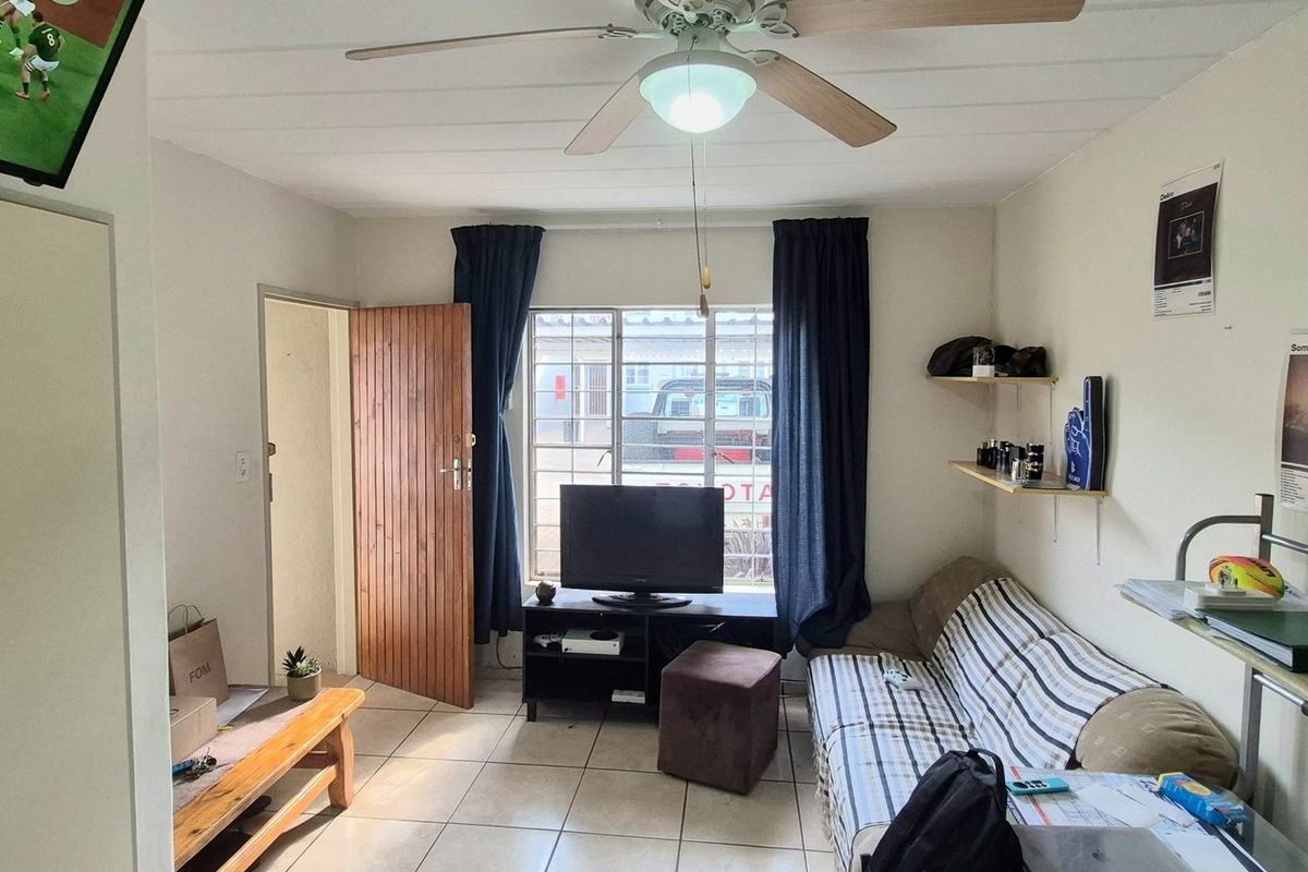 A functional living room featuring tiled flooring, a ceiling fan, and built-in shelving, providing a practical and comfortable living space.