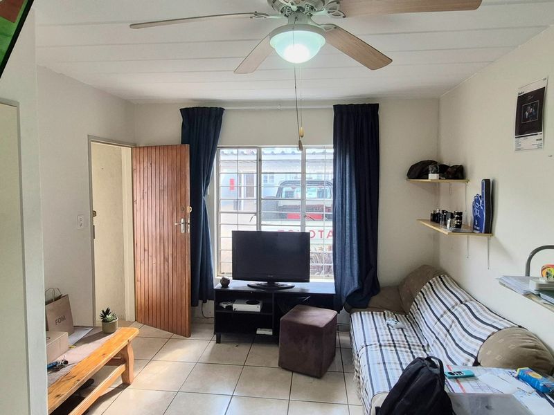 A functional living room featuring tiled flooring, a ceiling fan, and built-in shelving, providing a practical and comfortable living space.
