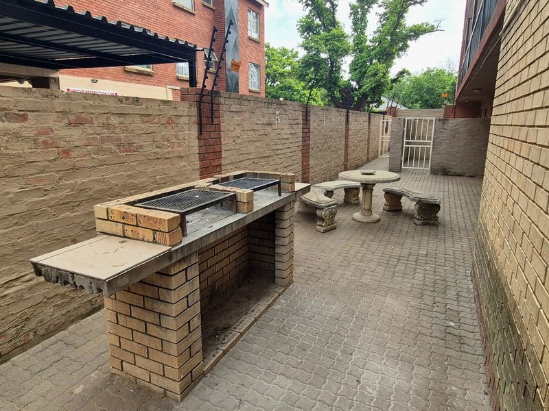 Outdoor patio area featuring a built-in brick braai, paved flooring, and enclosed by perimeter brick walls.