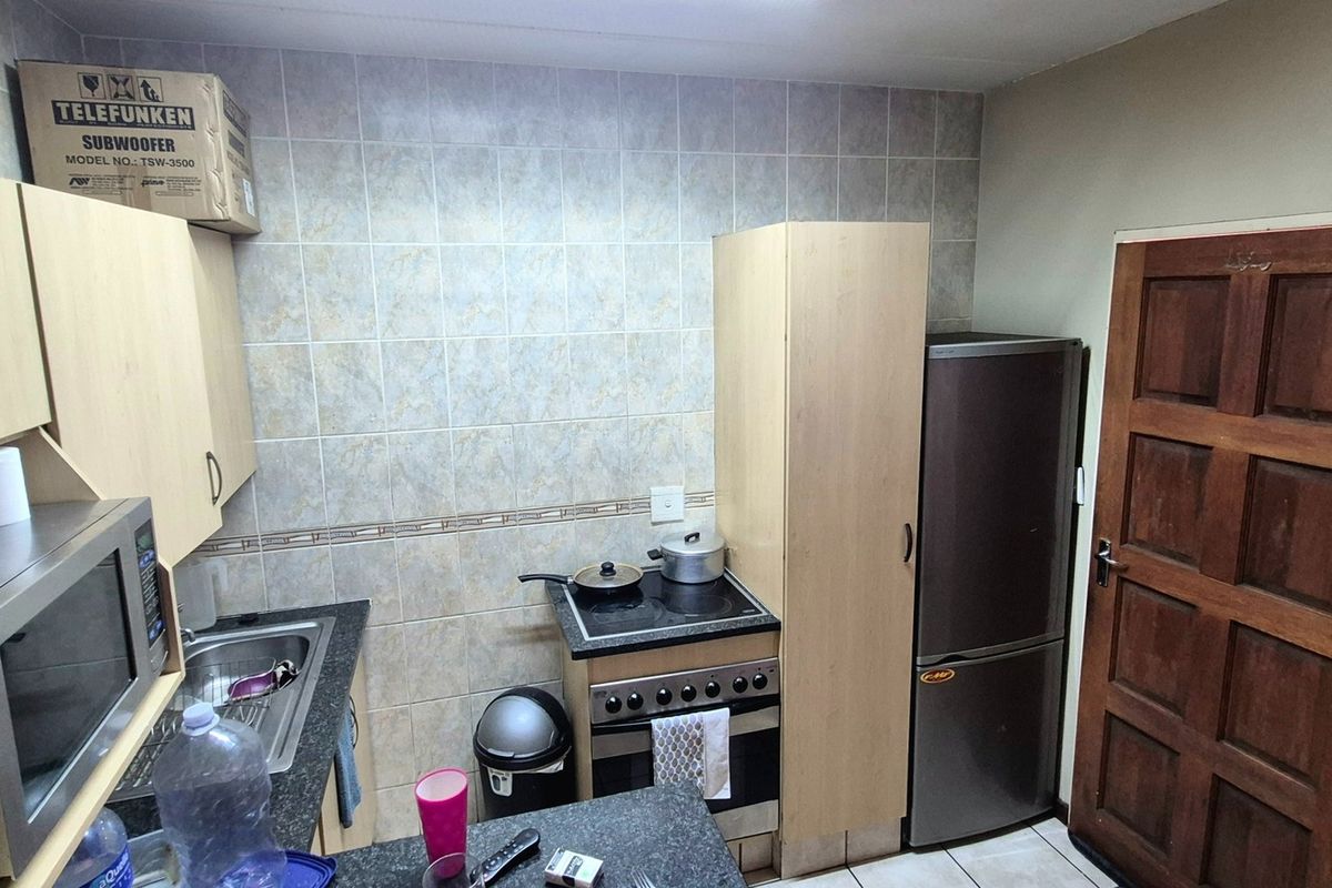 Compact kitchen featuring built-in cabinetry, laminate countertops, a tiled backsplash, and a functional electric stove and oven setup.