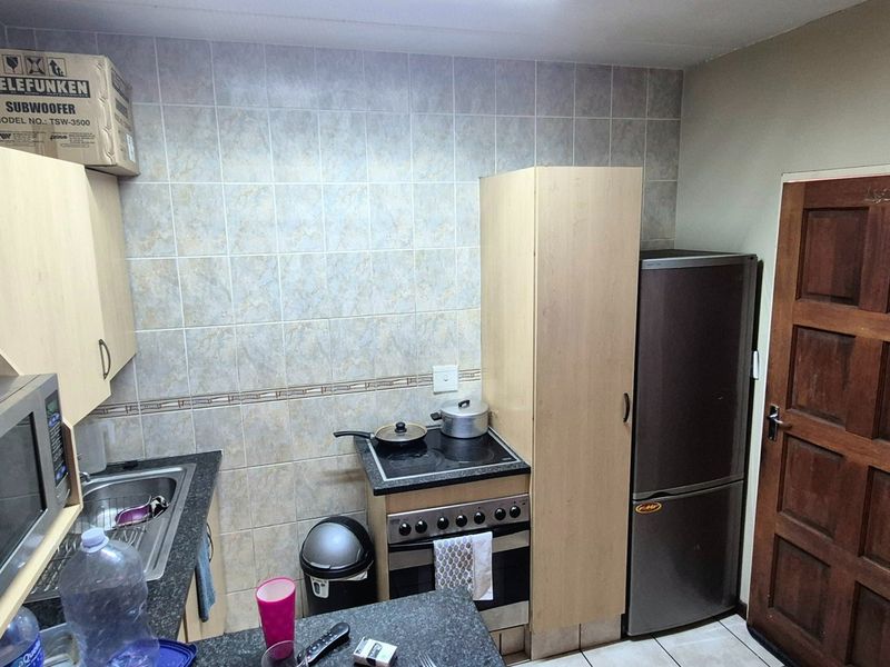 Compact kitchen featuring built-in cabinetry, laminate countertops, a tiled backsplash, and a functional electric stove and oven setup.