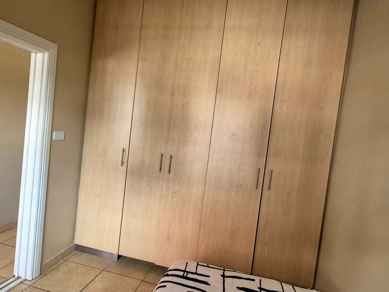 A bedroom featuring built-in wooden cupboards and tiled flooring, offering a functional storage solution within the apartment.