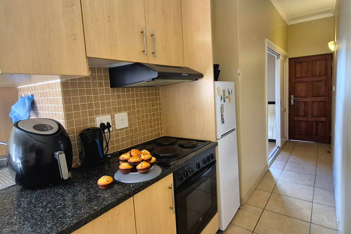 Compact kitchen featuring light wood cabinetry, dark laminate countertops, tiled backsplash, and integrated electric stove and oven.